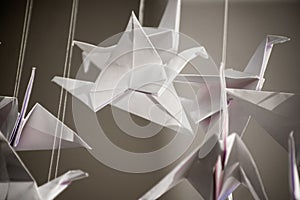 Japanese folded Origami cranes hanging on with strings. Hundreds handmade paper birds isolated with copy space. 1000