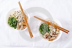 Japanese food. Bowl of rice, boiled white fish and wakame chuka or seaweed salad.