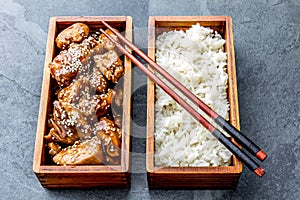 Japanese food. Chicken teriyaki with rice in wooden bento lunch box. slate background, top view.