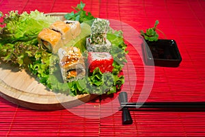 Japanese food restaurant platter set. Hand take roll. Set for two with chopsticks, ginger, soy, wasabi. Sushi at rustic wood backg