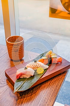 Japanese food,set of sushi put on a rectangular wooden plate and a cup of green tea beside