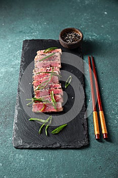 Japanese food. Tuna tataki. Raw tuna sashimi searahi con cesamo on black board