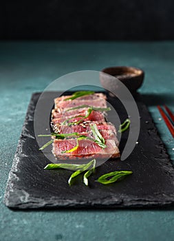 Japanese food. Tuna tataki. Raw tuna sashimi searahi con cesamo on black board