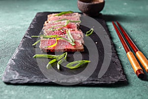 Japanese food. Tuna tataki. Raw tuna sashimi searahi con cesamo on black board