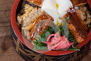Japanese fusion dish with spicy rice with tamari sauce, roasted eel, egg and red turnip