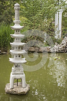 Japanese garden lantern on water background.