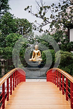 Japanese garden, red bridge and golden Buddha statue of Kawasaki