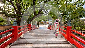A Japanese Geisha in Traditional Kimono Costume cross the Bridge at Dazaifu Tenmangu Shrine in Fukuoka