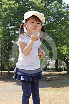 Japanese girl blowing dandelion seeds under the blue sky