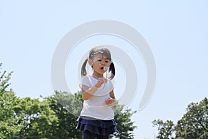 Japanese girl blowing dandelion seeds under the blue sky