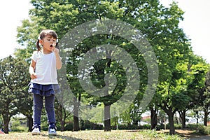 Japanese girl blowing dandelion seeds under the blue sky