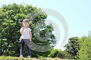 Japanese girl blowing dandelion seeds under the blue sky