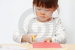 Japanese girl cutting paper with scissors