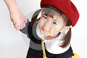 Japanese girl in kindergarten uniform clasping her mother`s hand