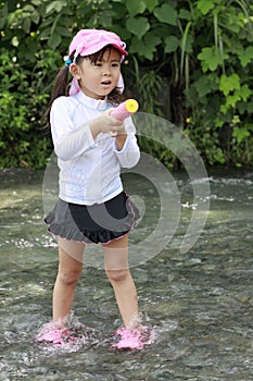 Japanese girl playing in the river with water gun