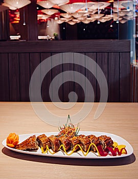 Japanese grilled Unagi Maki roll on white plate dark background