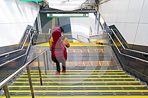 Japanese guy walking down the stair at the train station with the guitar backpack on his back