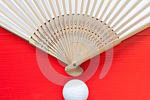 Japanese hand fan made and golf balls on the red table