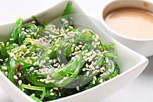 Japanese hiyashi wakame chuka salad with white sesame seeds and peanut sauce in a bowl on a white background