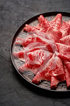 Japanese kobe beef sliced on ceramic plate on black background