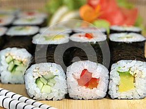 Japanese maki roll set with avocado, cucumber and red bell pepper on a wooden tray close-up