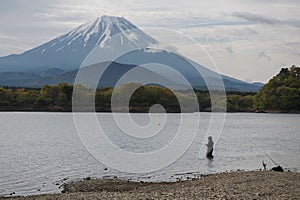 Japanese man fishing on Shoji lake with mount Fuji view