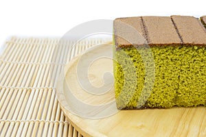 Japanese Matcha green tea cake cheesecake on wooden plate and traditional mat white background.