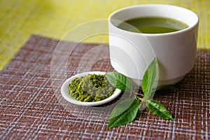 Japanese matcha green tea is poured into a white mug and on a white saucer in powder.