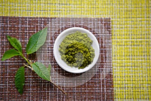 Japanese matcha green tea is poured into a white mug and on a white saucer in powder.