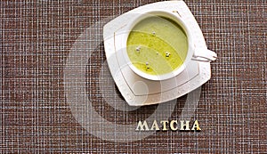 Japanese matcha green tea is poured into a white mug and on a white saucer in powder. Inscription in wooden letters in English. Te