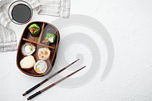 Japanese Meal in a Box Bento with sushi roll eice avocado salmon fish, on white stone  background, top view flat lay , with