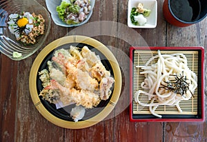A Japanese meal on a wooden table. Zaru udon served with tempura mori, ika natto and takowasabi as a side dish. Top view