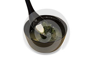 Die cut Japanese miso soup in a black bowl with a spoon on white background