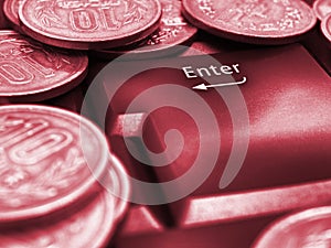 Japanese money coins and Enter button close up. Coins in 10 yen lie on the keyboard of a computer or laptop. Red tinted