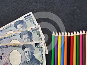 Japanese money and color pencils on the black background