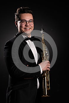 Japanese Musician Saxophonist in a Black Classic Suit Holds a Soprano Straight Saxophone in his Hand and Poses for the