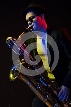 Japanese Musician Saxophonist Holds a Soprano Straight Saxophone in his Hand and Poses for Camera on a Black Background
