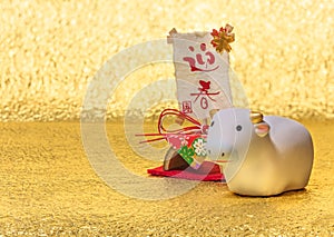 Japanese New Year`s Card with a figurine of cow for the 2021 Year of the Ox on a golden background.