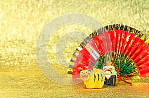 Japanese New Year`s Greeting Card of a roaring tiger with a folding fan and kagami mochi on gold background.