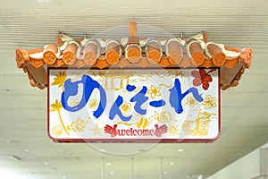 Japanese Okinawan Mensore sign which means Welcome decorated with a traditional house roof decorated with a lion Shisa in the