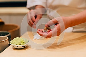 Japanese Omakase Chef making Chutoro Sushi Medium Fatty Bluefin Tuna, pasting fresh wasabi neatly by hands.