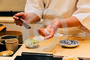 Japanese Omakase making Trout Sushi and adding Shoyu sauce on fish neatly by brush in his palm.