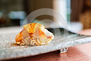 Japanese Omakase meal: Grilled Shrimp Sushi with Torched Mentaiko Sauce served by hand on a stone plate.