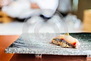 Japanese Omakase meal: Shima Aji Sushi with fresh wasabi served by hand on a stone black plate.