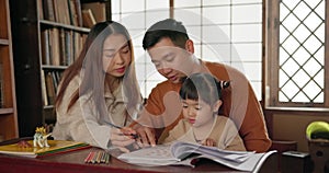 Japanese parents, child and education with homework, writing and books for study, development and helping hand. Dad