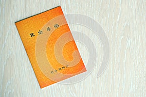 Japanese pension insurance booklet on table. Orange pension book for japan pensioners