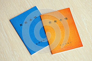 Japanese pension insurance booklets on table. Blue and orange pension book for japan