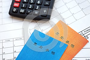 Japanese pension insurance booklets on table with calculator on table