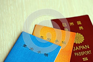 Japanese pension insurance booklets on table with passport. Blue and orange pension book