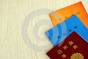 Japanese pension insurance booklets on table with passport. Blue and orange pension book